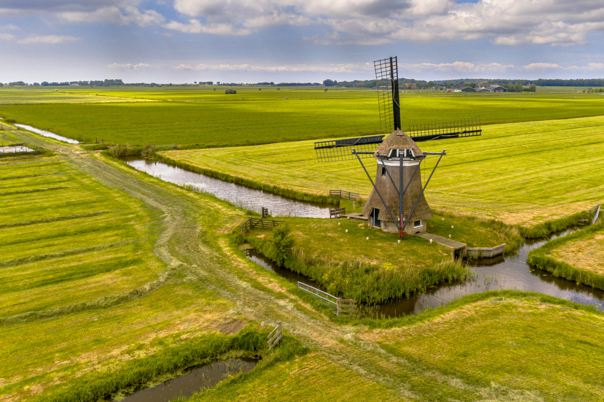 Old wooden windmill in green agricultural grassland